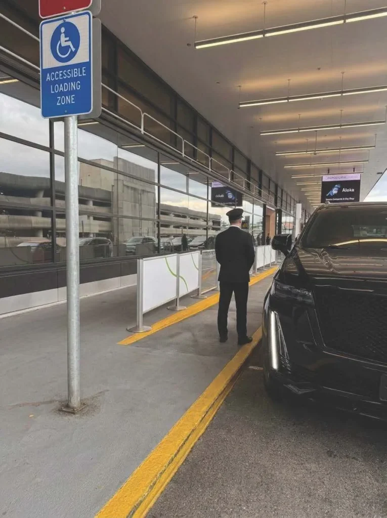 Uniformed Black Diamond chauffeur waiting at the Sea-Tac curb beside a black Escalade
